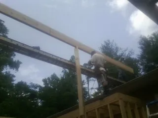 Carpenter setting a ridge beam over a new addition frame — Ice Dam Removal by Roofing Brothers in Groton
