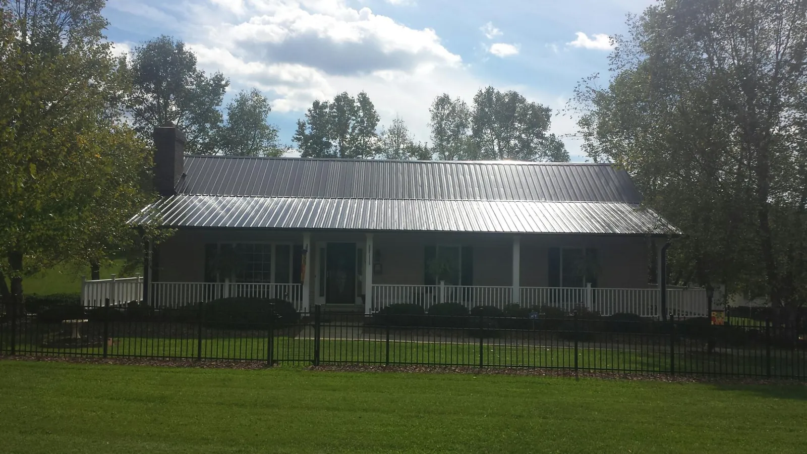 Gray metal roof on a brick ranch with a full width front porch — Gutter Guard Installation work by our crew in Groton